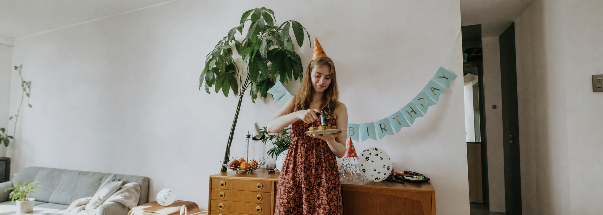 A woman in a party hat holding a birthday cake