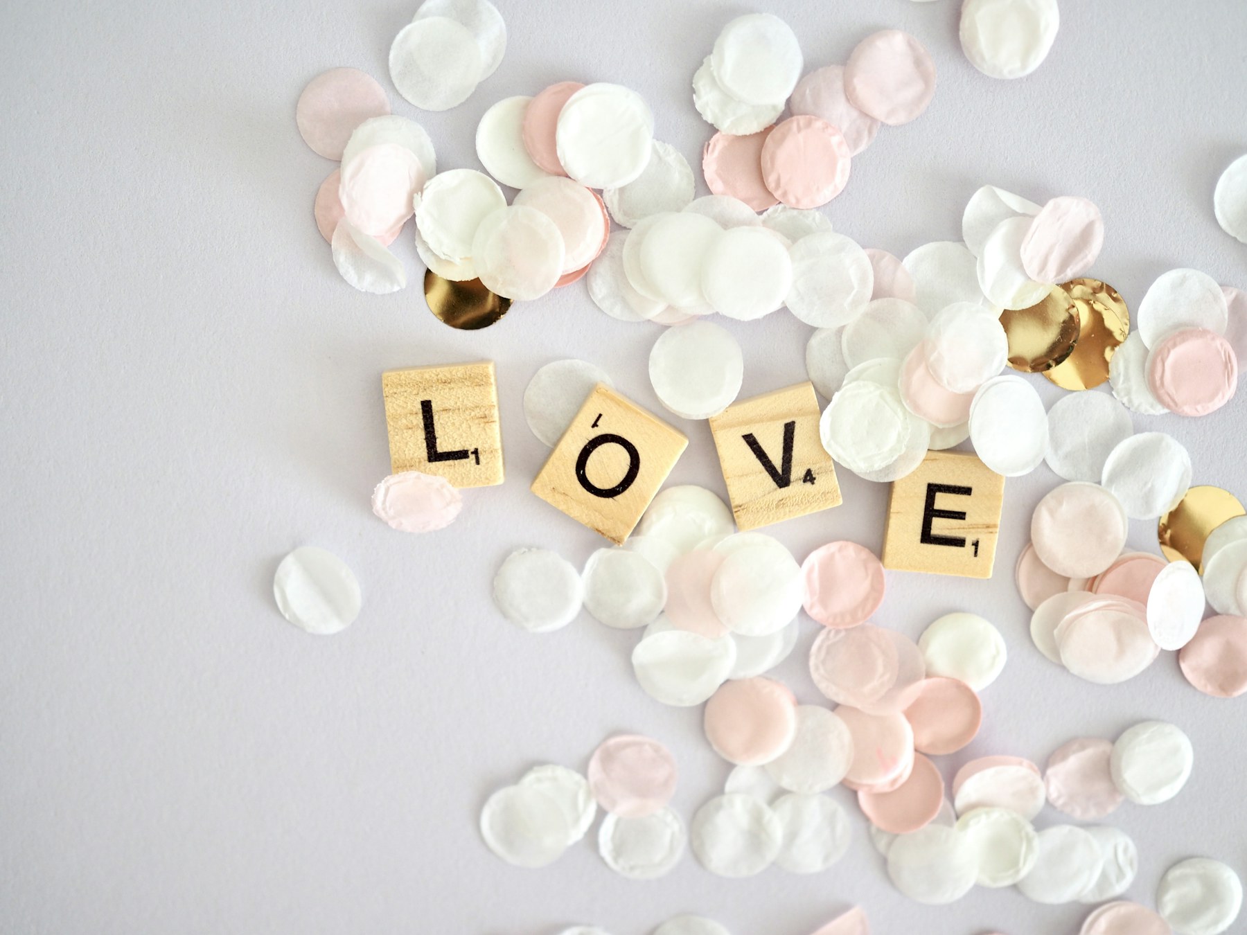 Pink and white wedding confetti surrounding wooden tiles spelling love