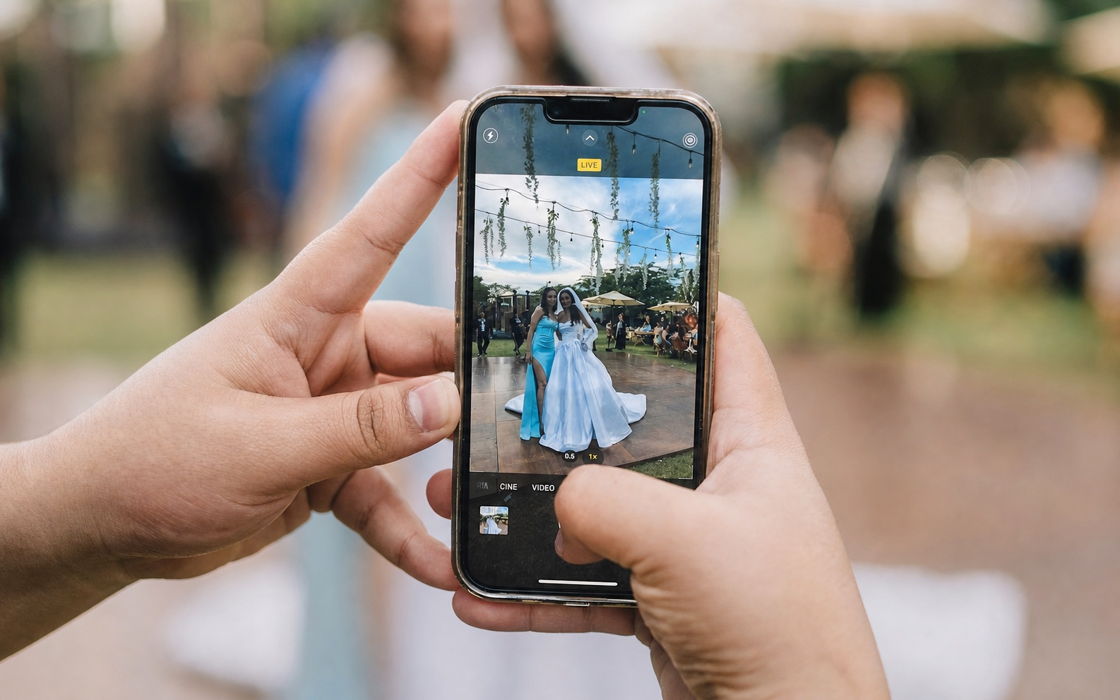 A wedding guest using a phone to photograph the bride during the reception