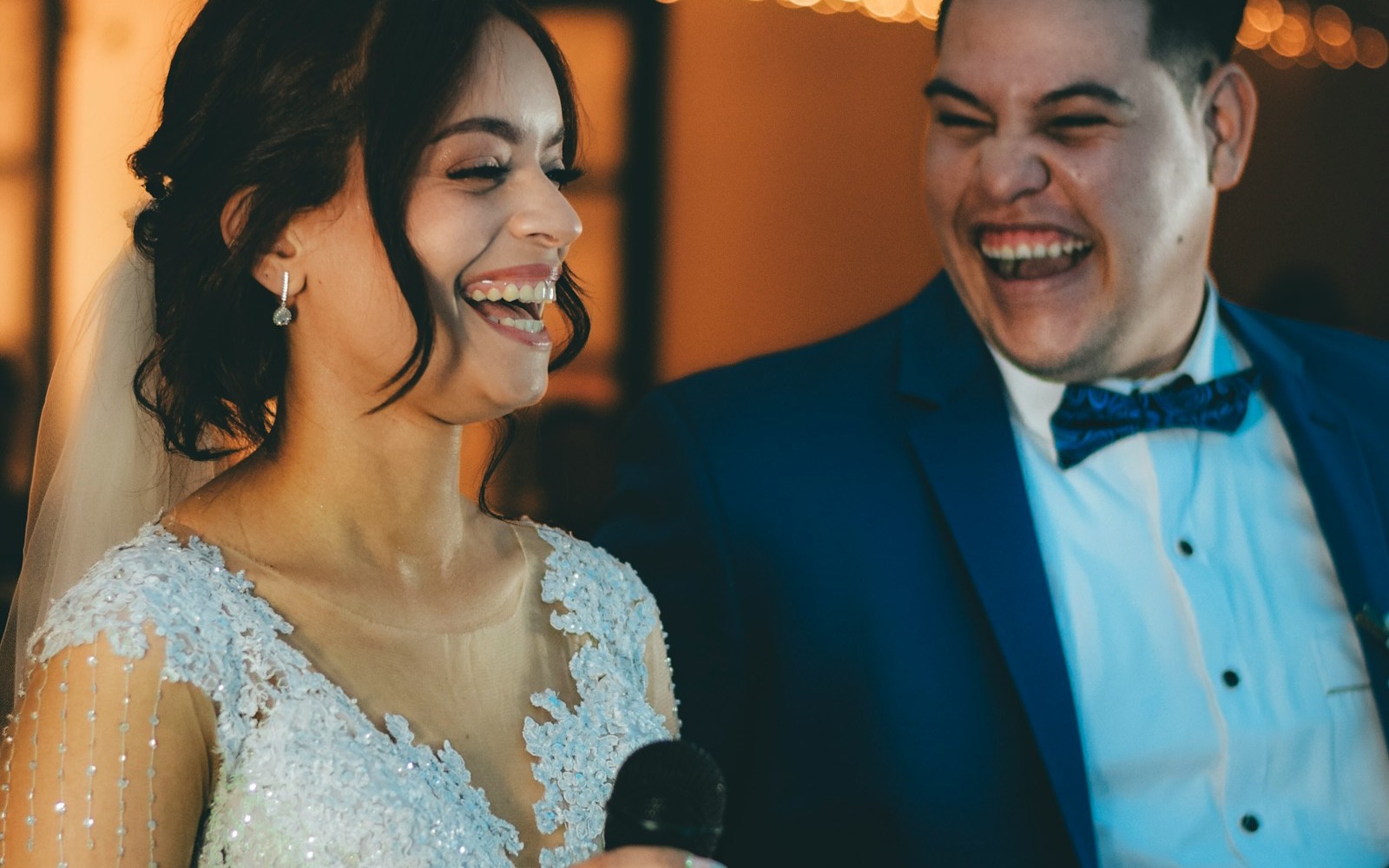 A bride and groom laughing together during a wedding speech