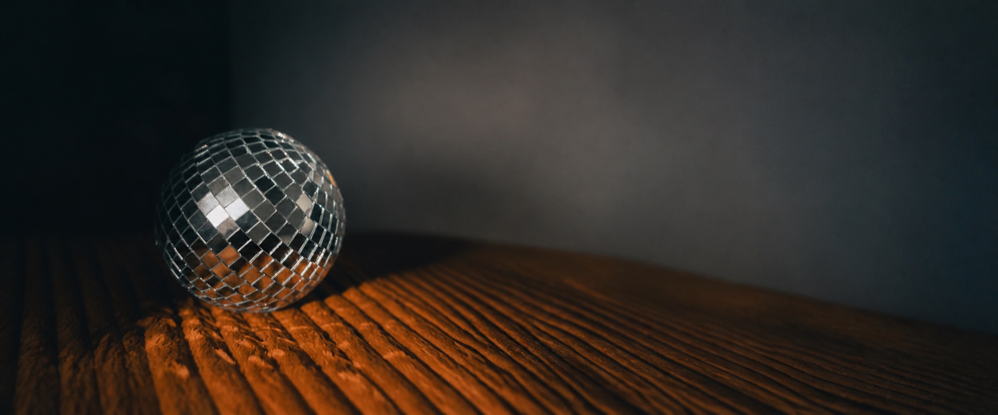 A mirrored disco ball glowing in warm light on a wooden surface